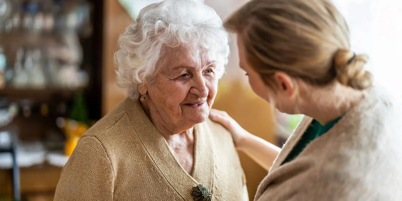 An older woman and a younger woman sitting together in a front room, talking and smiling