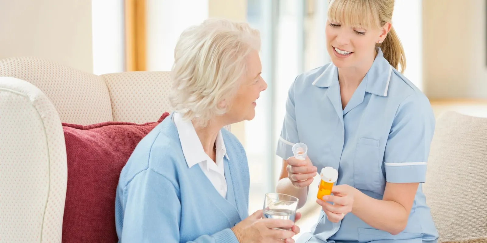 A carer sitting with an older woman, both smiling